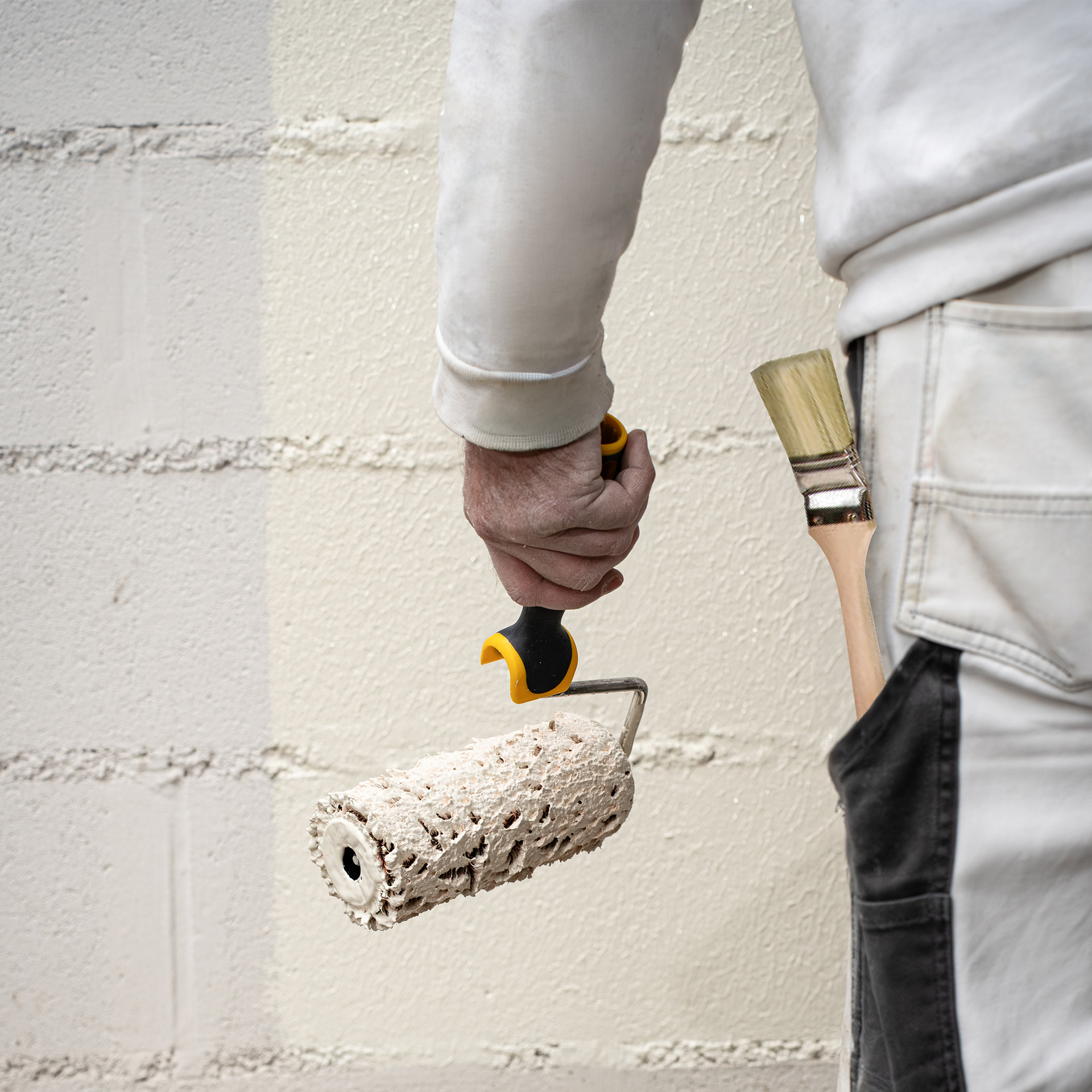 homme-pinceau-blanc Peintre avec pinceau Roulor DuoPile à la main devant un mur blanc